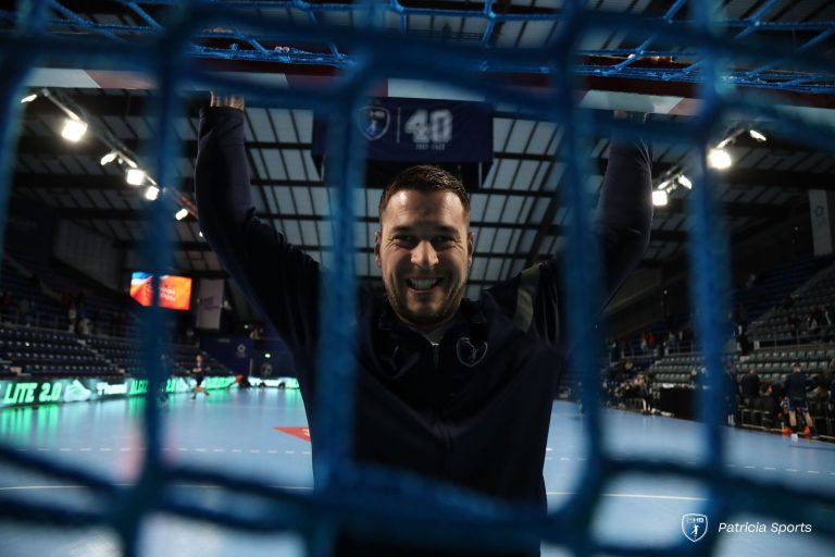 Homme souriant accroché à un filet au stade.