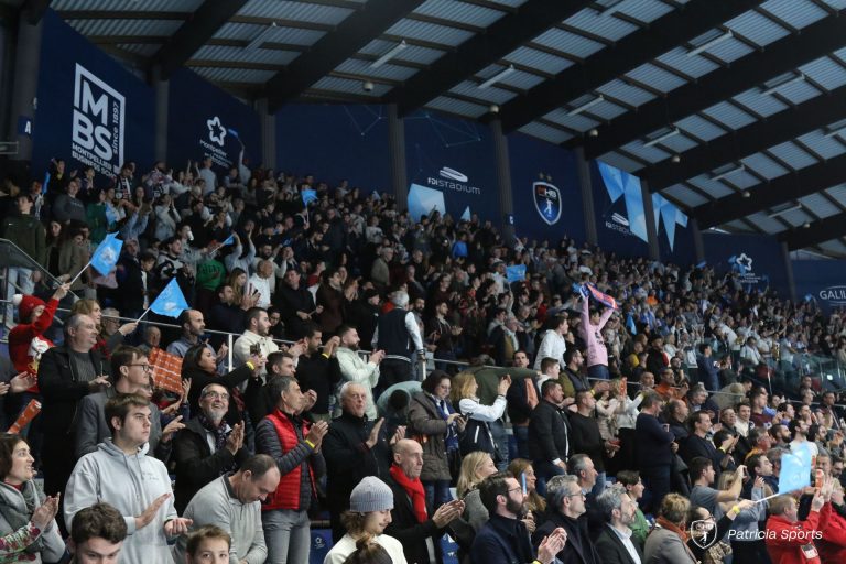 Supporters applaudissant dans un stade bondé.