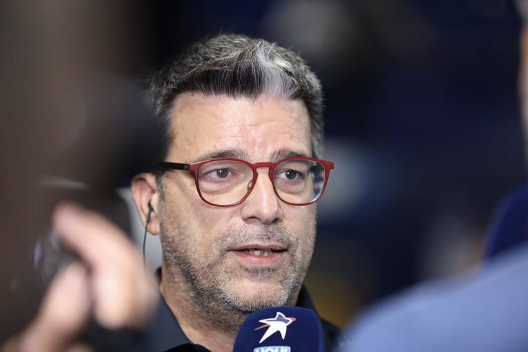 Homme portant des lunettes rouges en interview.