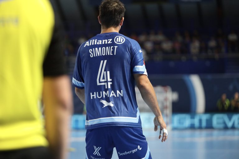 Joueur de handball en tenue bleue sur le terrain.