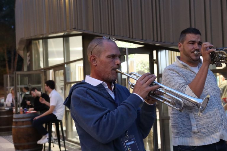 Deux musiciens jouent de la trompette en extérieur.