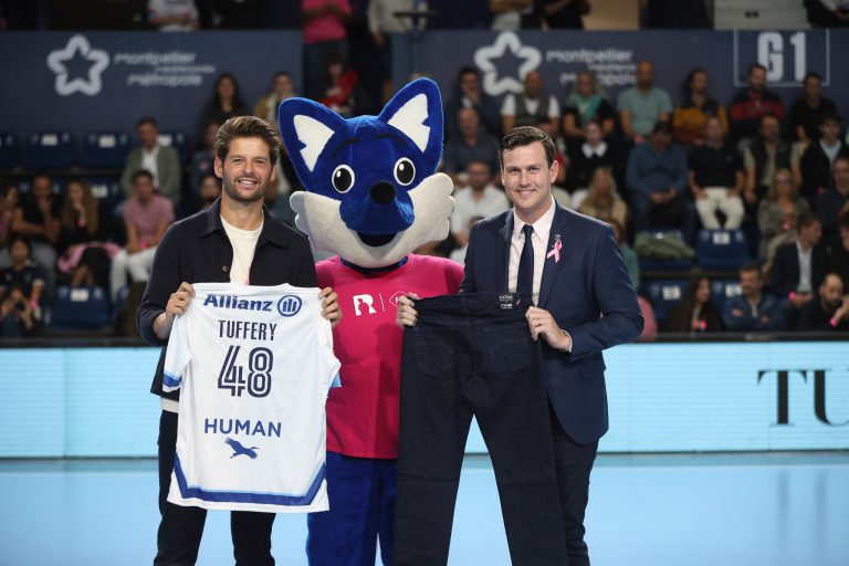 Deux hommes avec mascotte et maillot sportif.
