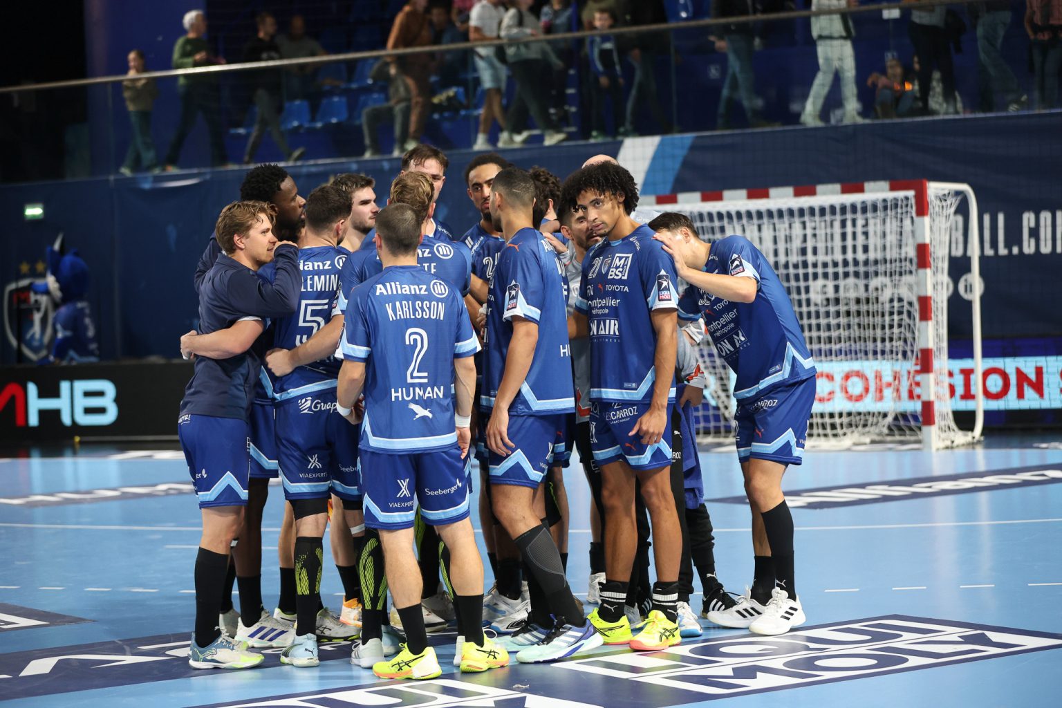 Équipe de handball en cercle sur le terrain.