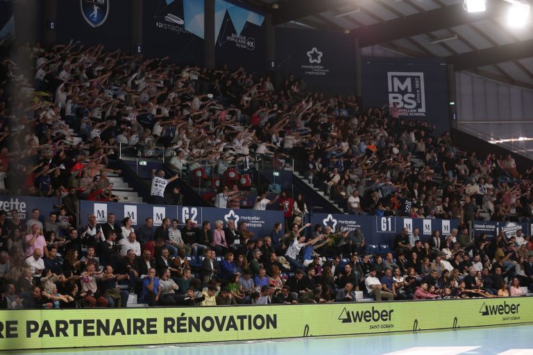 Supporters enthousiastes dans une salle de sport comble.