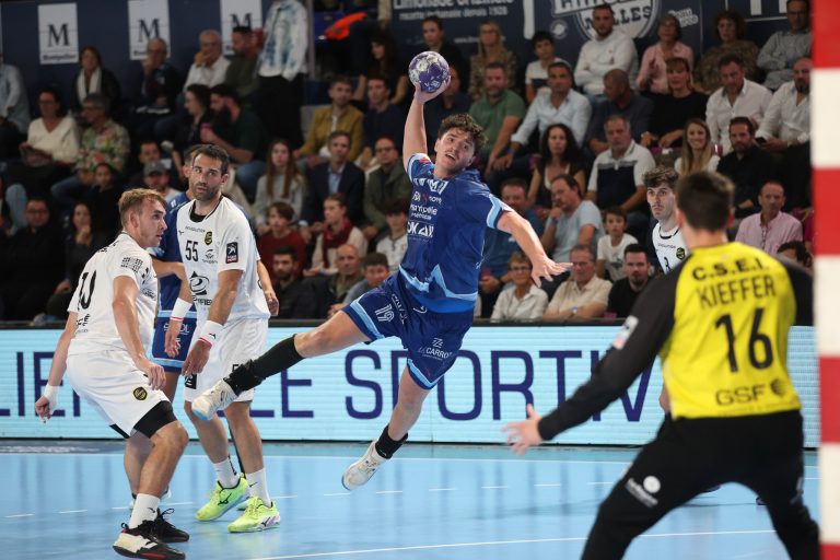 Match de handball en action avec joueurs et spectateurs.