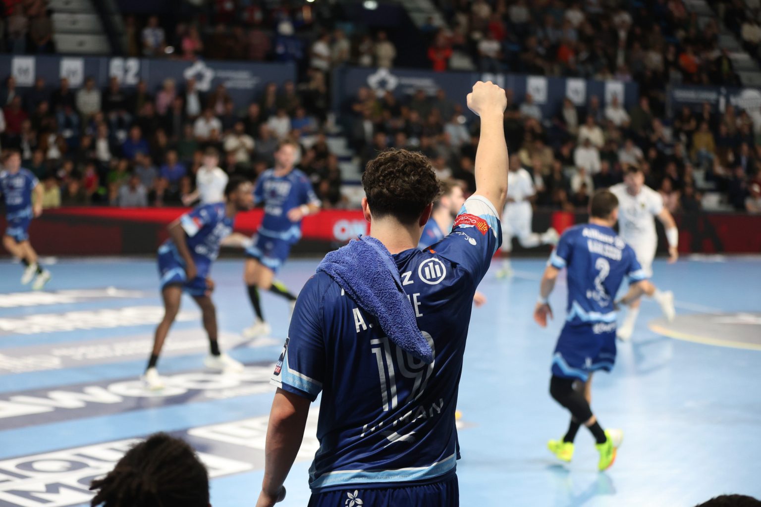 Joueur de handball encourageant l'équipe sur le terrain.