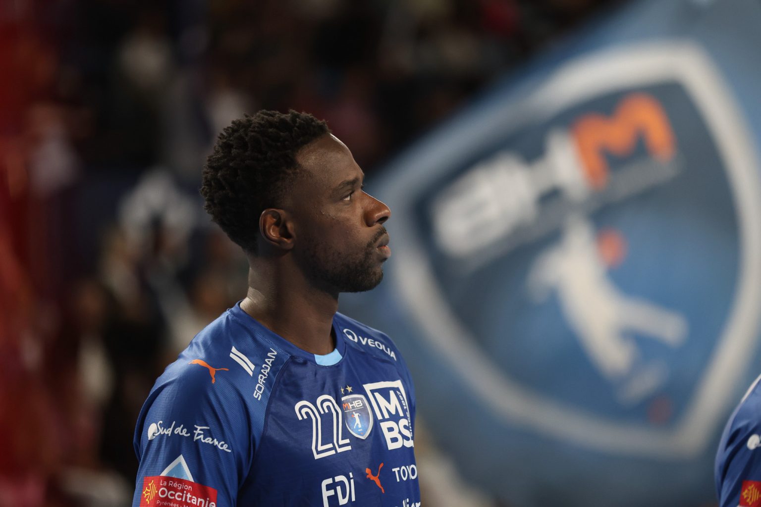 Joueur de handball en maillot bleu sur le terrain.
