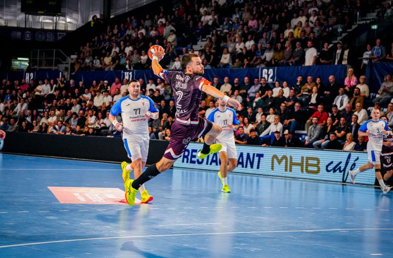 Match de handball en cours dans une arène bondée.