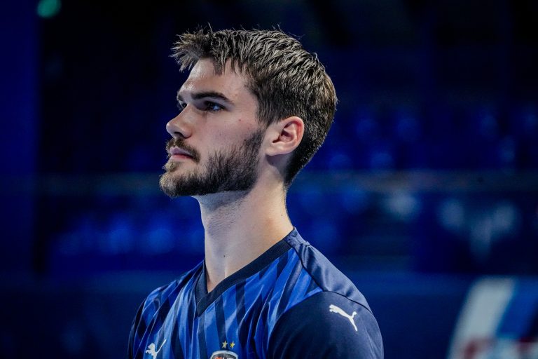Joueur de football en maillot bleu observant vers l'avant.