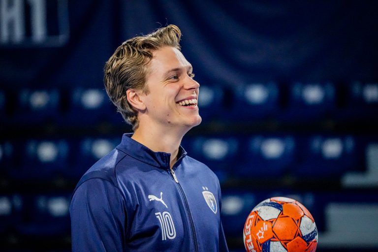Joueur souriant en tenue de handball avec ballon.