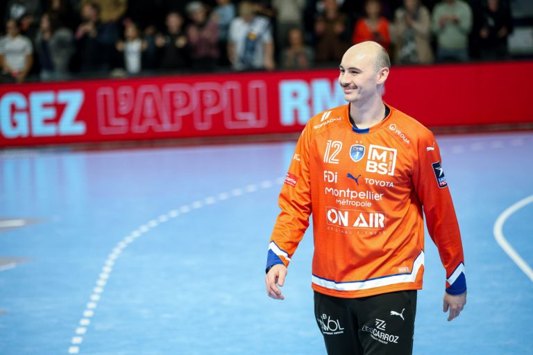 Joueur de handball en maillot orange sur le terrain.