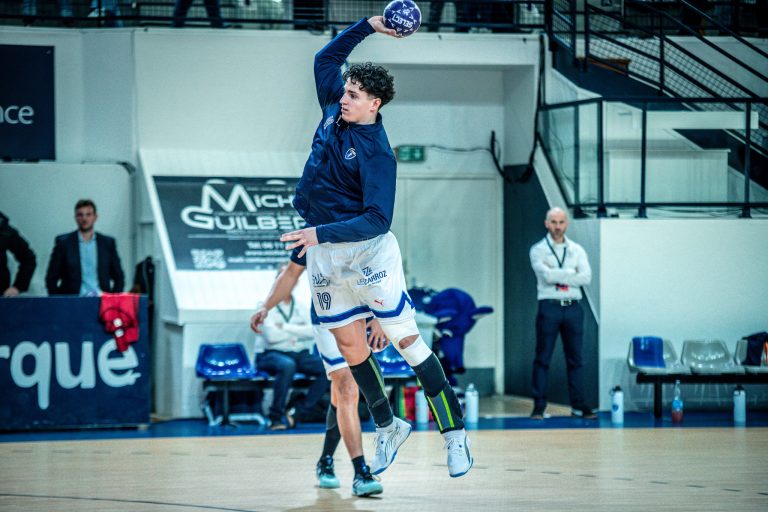 Joueur de handball en pleine action de saut.
