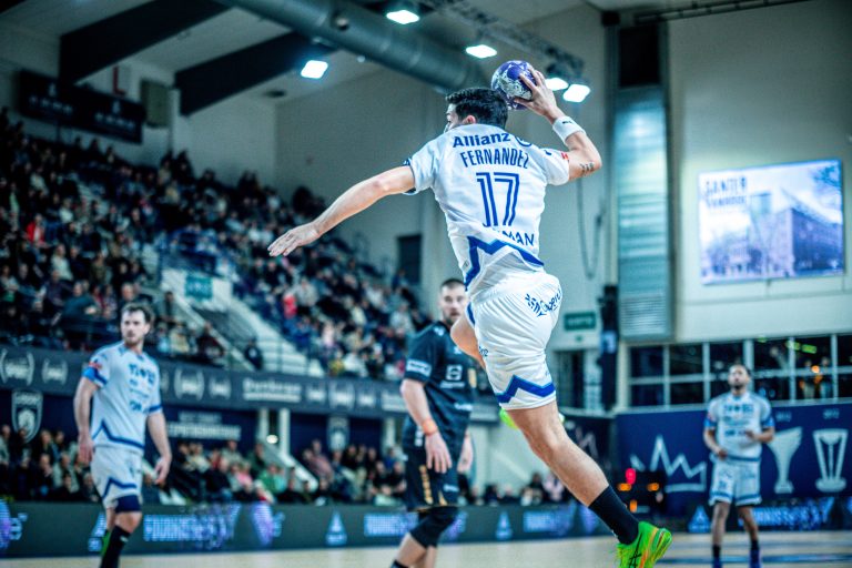 Joueur de handball en plein saut, match en salle.