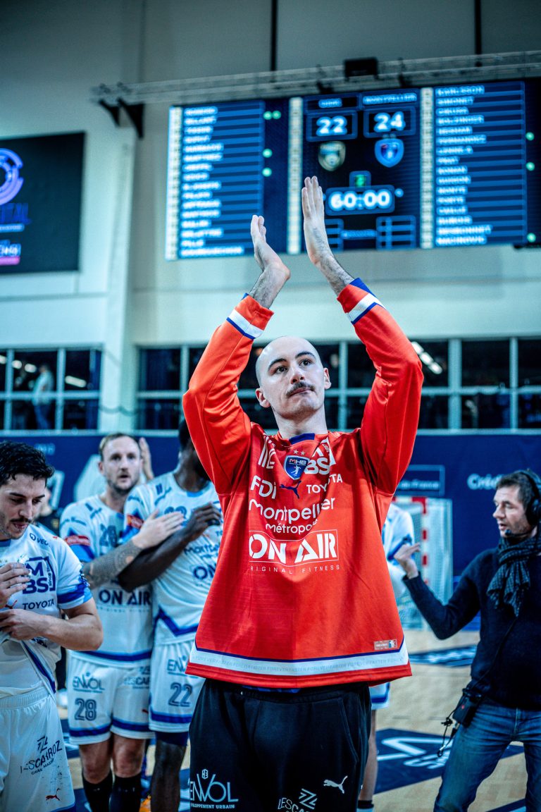 Joueur de handball applaudissant sur le terrain.