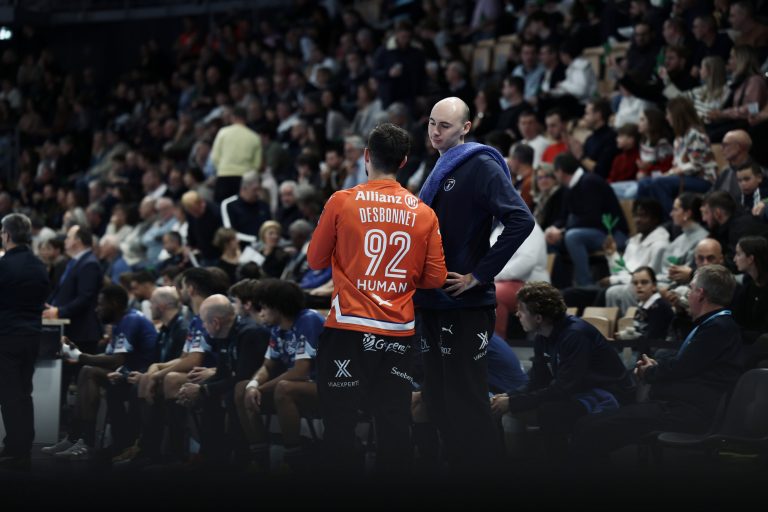 Joueurs de handball discutant sur le banc pendant un match.