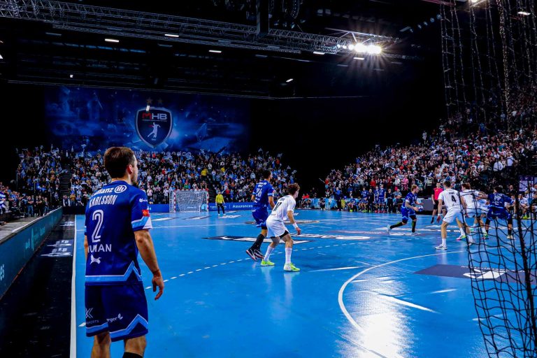 Match de handball, joueurs en action, foule enthousiaste.