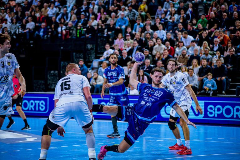 Match de handball en action, joueur marquant but.