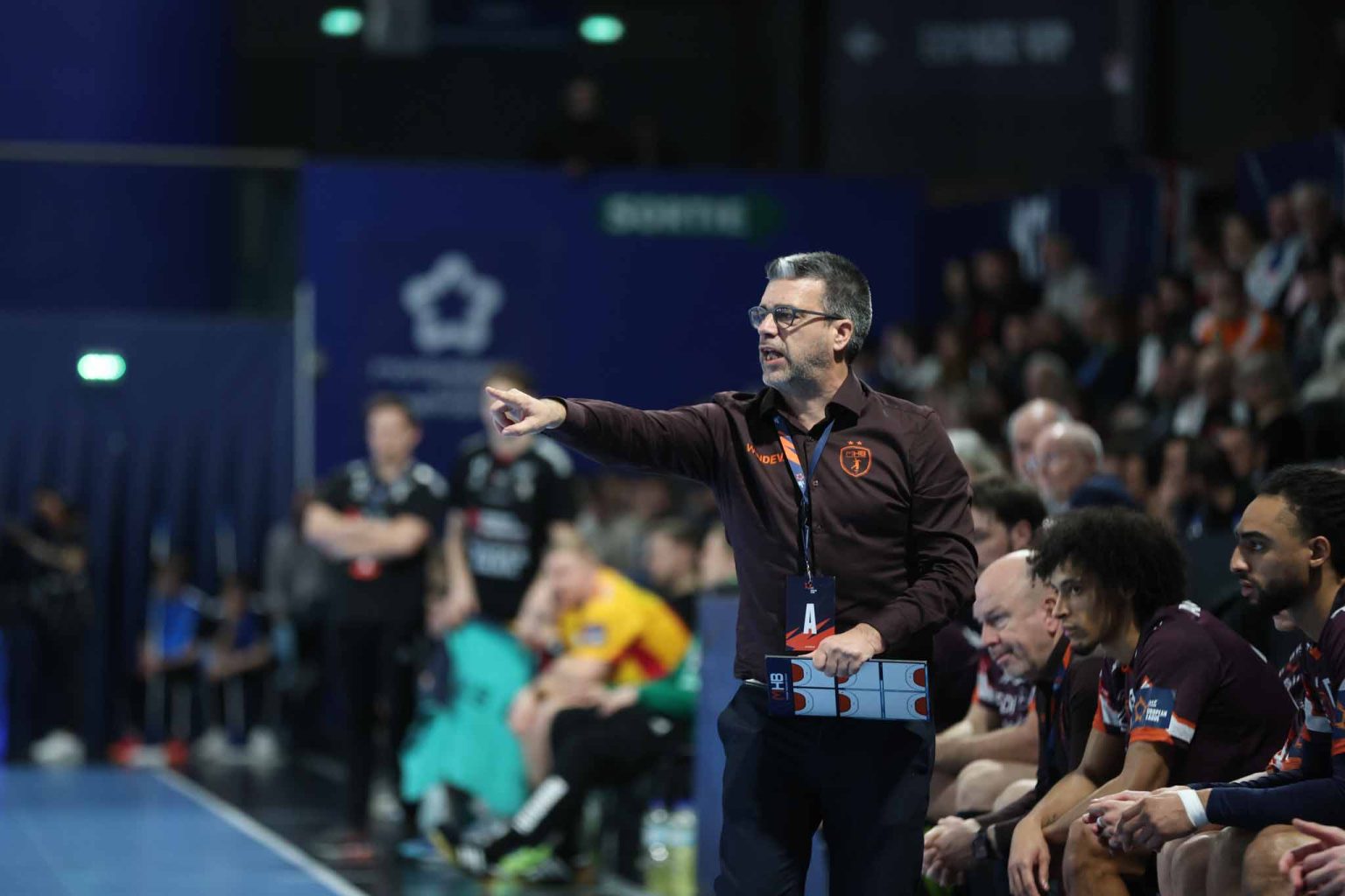 Entraîneur de handball donne des instructions sur terrain.