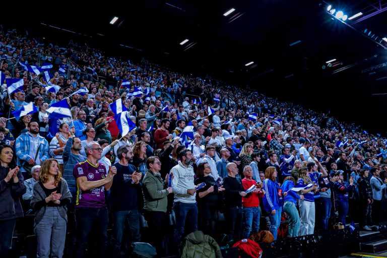 Foule enthousiaste avec drapeaux dans un stade.