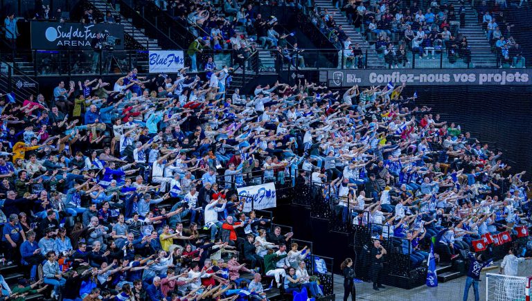 Supporters enthousiastes dans les gradins d'une arène sportive.