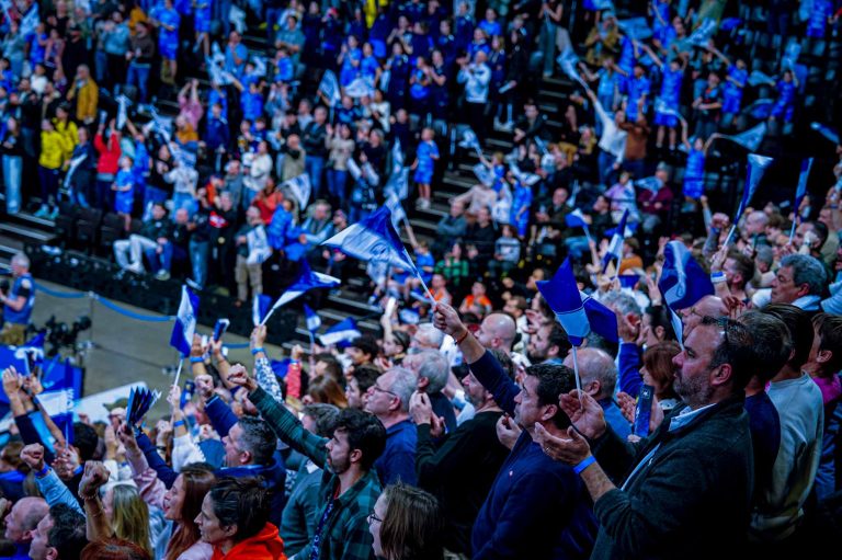 Supporters enthousiastes avec drapeaux dans une foule sportive.