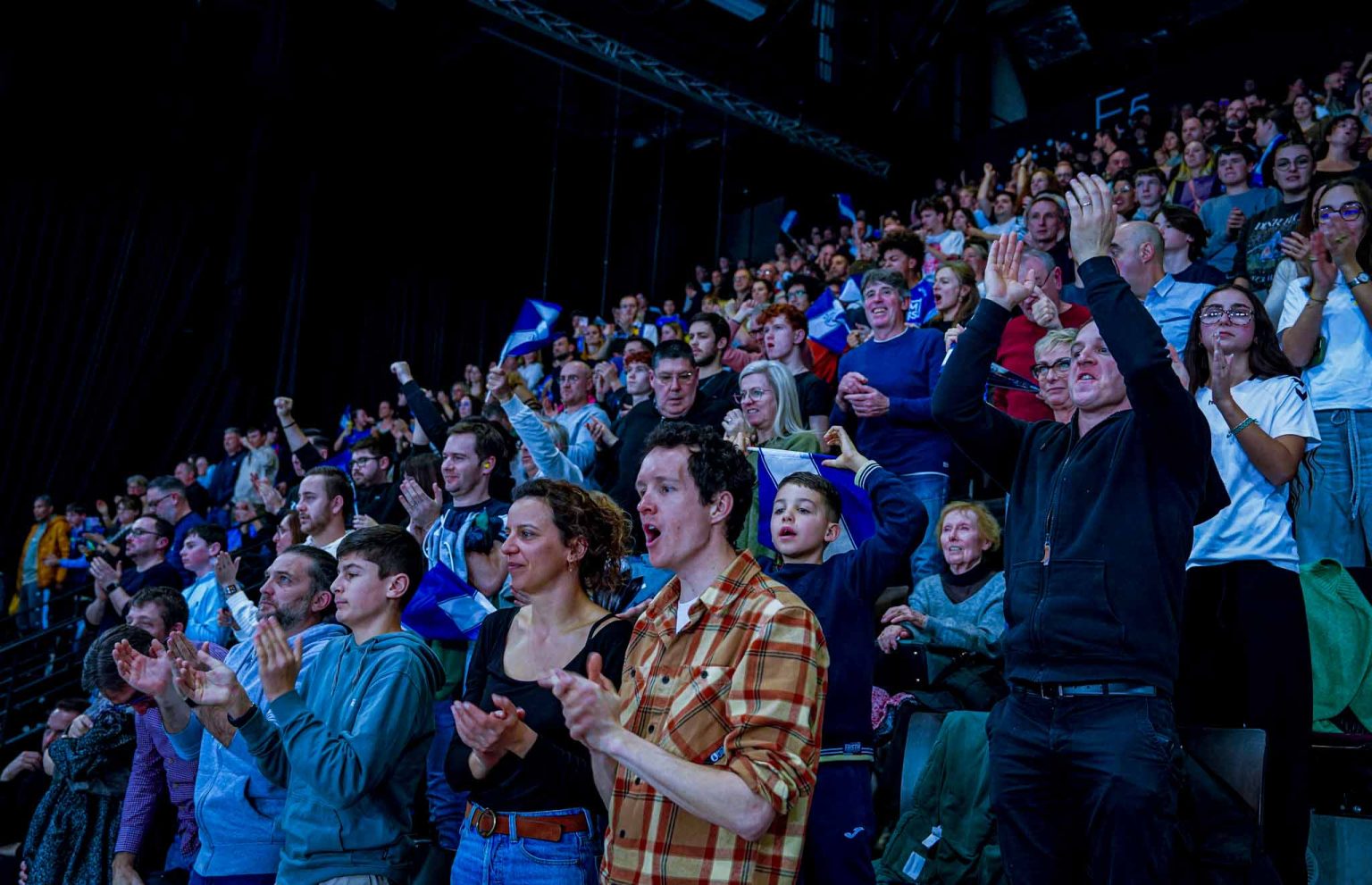 Foule enthousiaste applaudissant dans une salle de spectacle.