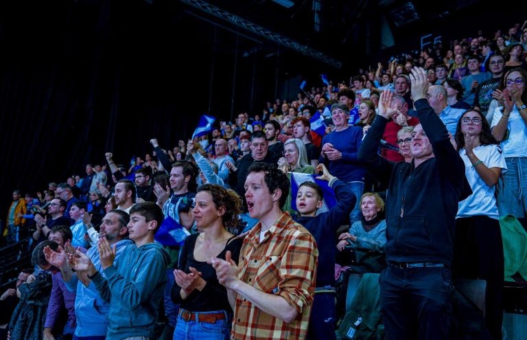 Foule enthousiaste applaudissant dans une salle de spectacle.