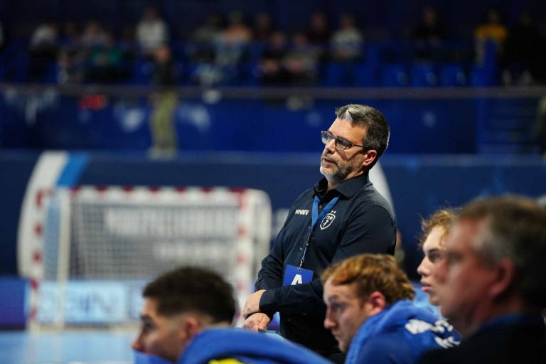 Entraîneur observe match de handball depuis le banc.