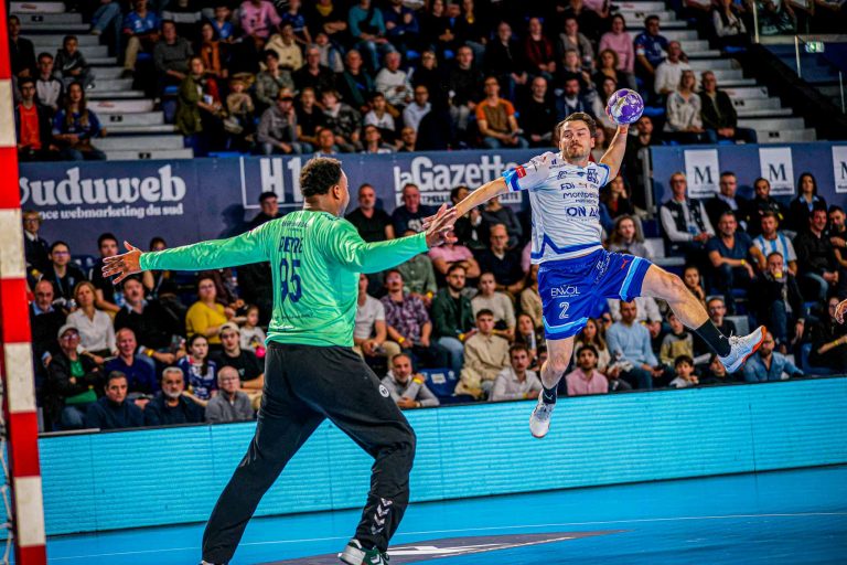 Match de handball en action, joueur tire au but.