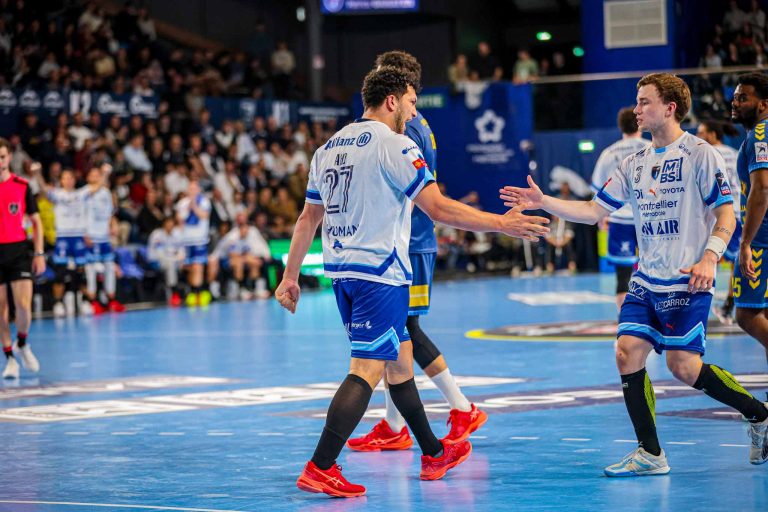 Joueurs de handball se félicitant sur le terrain.