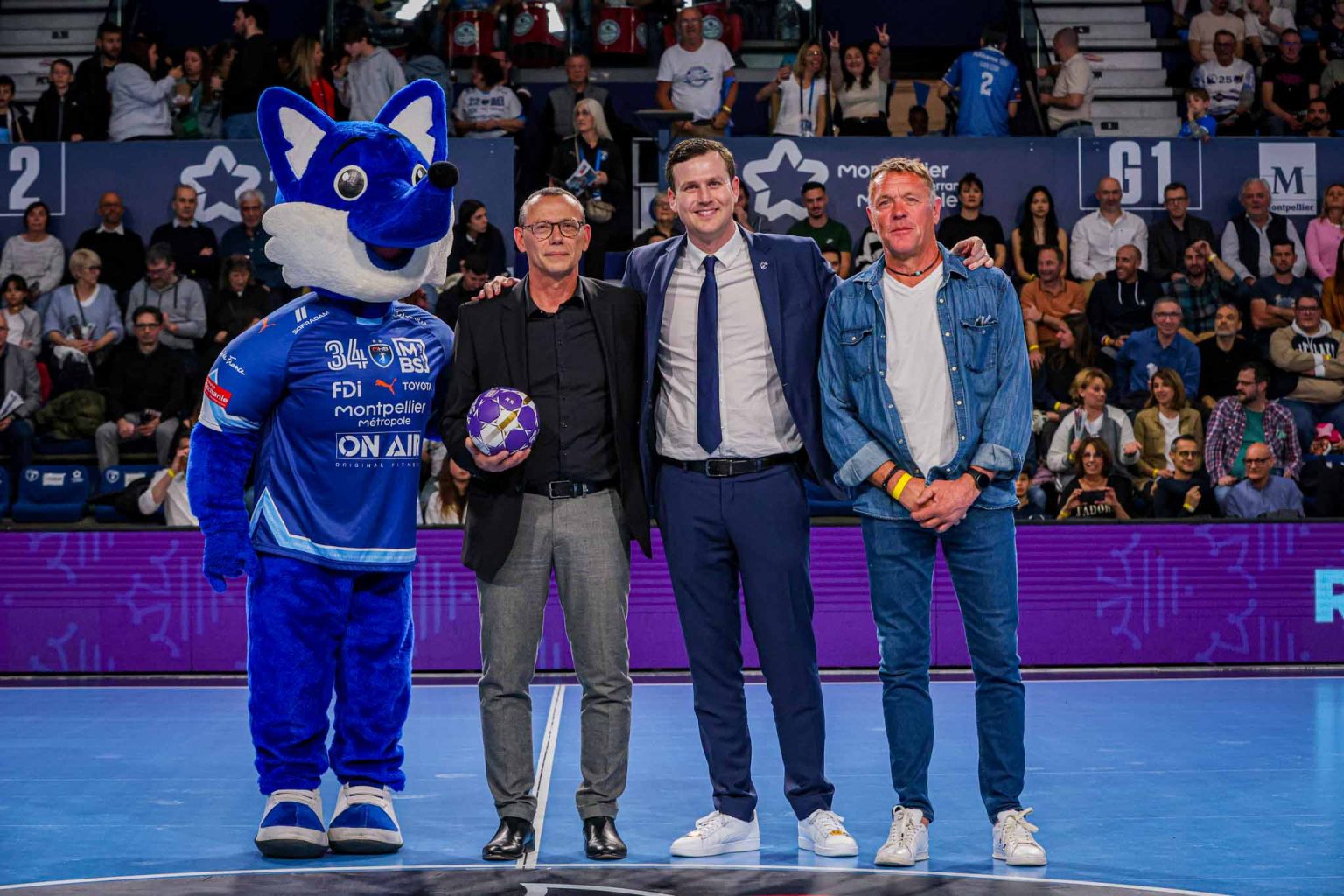 Personnes posant avec mascotte bleue à l'événement sportif.