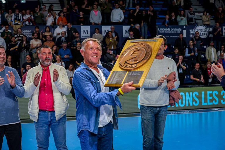 Homme avec trophée, foule applaudit en arrière-plan.