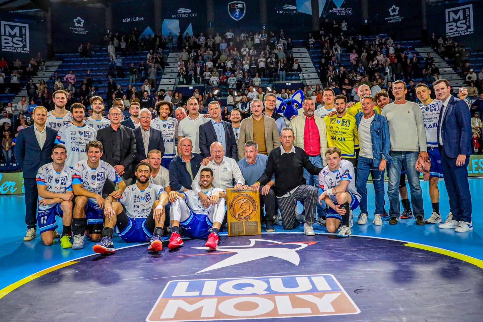 Équipe de handball posant avec trophée au stade.
