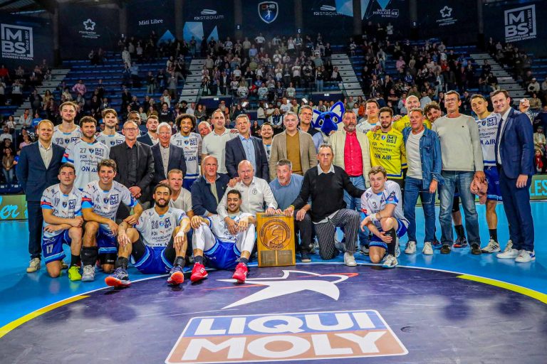 Équipe de handball posant avec trophée au stade.