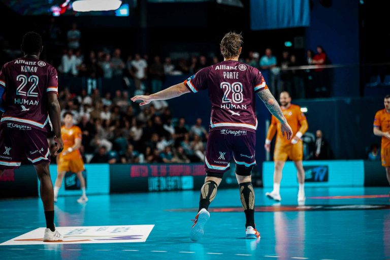 Match de handball en cours avec joueurs sur terrain.