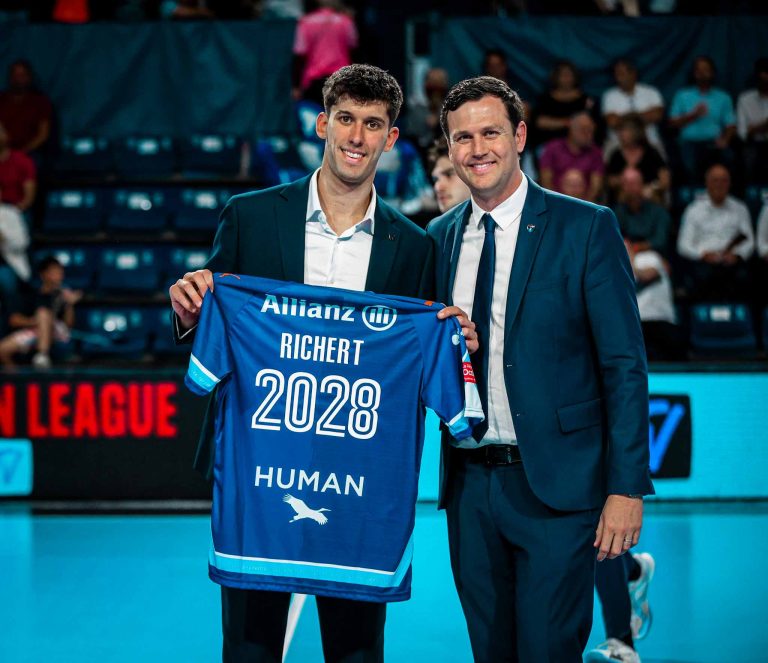 Homme tenant maillot signé Richert 2028, souriant.