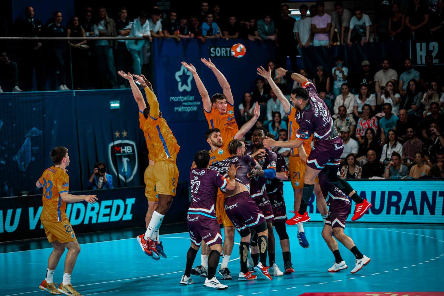 Match de handball intense avec joueurs en action.