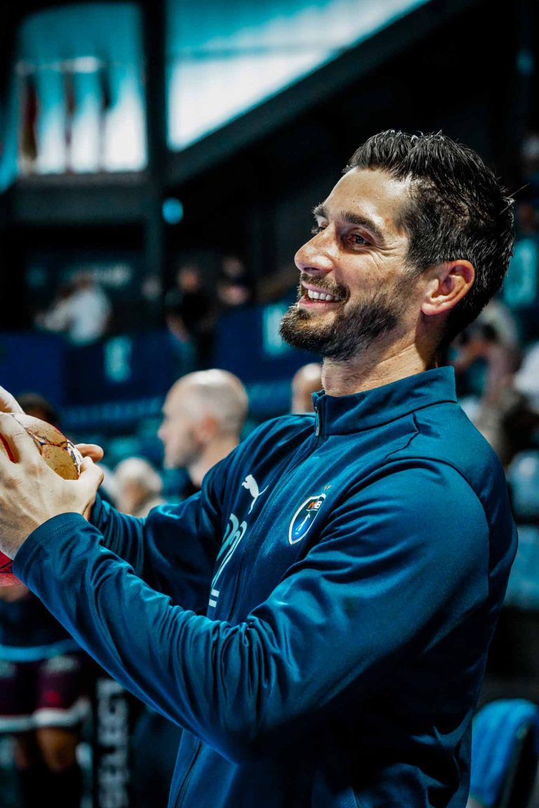 Joueur de handball souriant tenant le ballon.