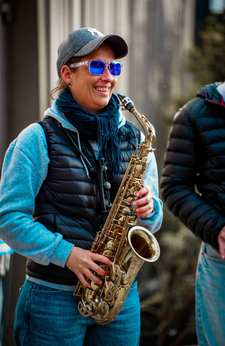 Femme souriante jouant du saxophone en plein air.