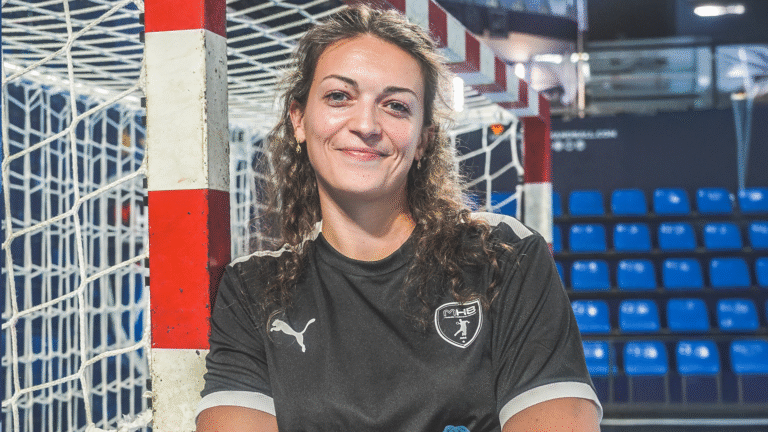 Femme souriante devant un but de handball.