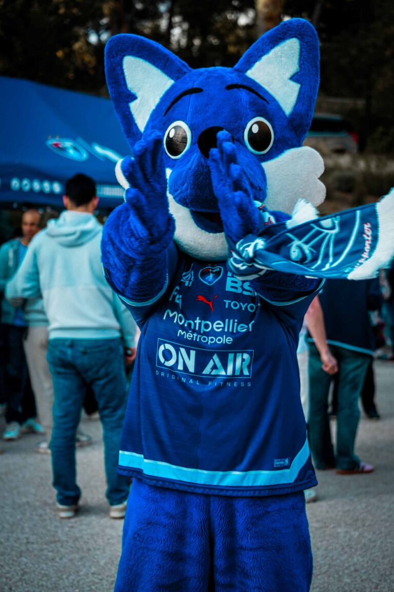Mascotte bleue chaleureuse lors d'un événement sportif.