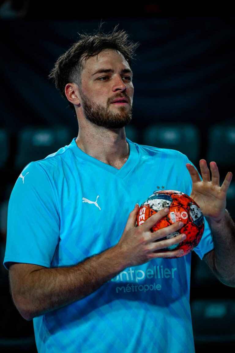 Joueur de handball tenant un ballon sur le terrain.