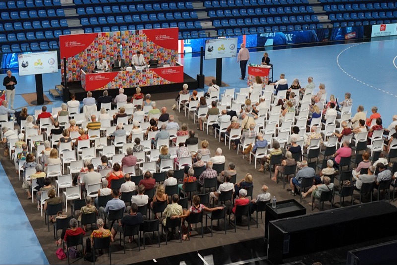 Conférence publique dans une salle remplie de personnes.