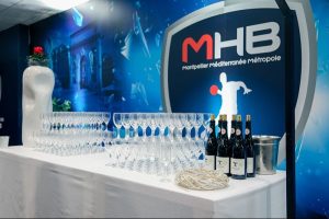 Table avec verres et bouteilles devant logo MHB.