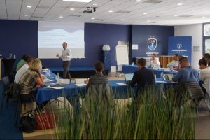 Conférence professionnelle avec présentateur et participants.