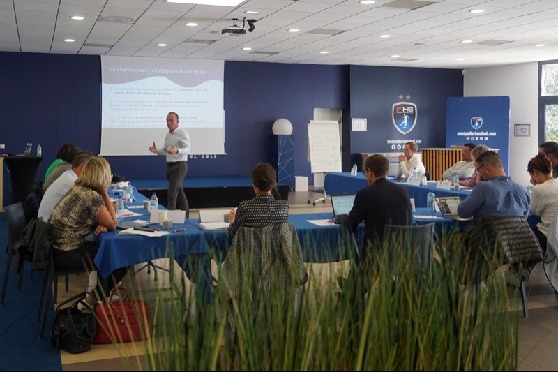 Conférence professionnelle avec présentateur et participants.
