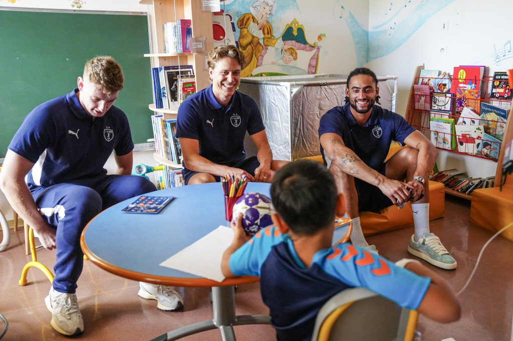 Enfants et adultes sourient dans une salle de classe.