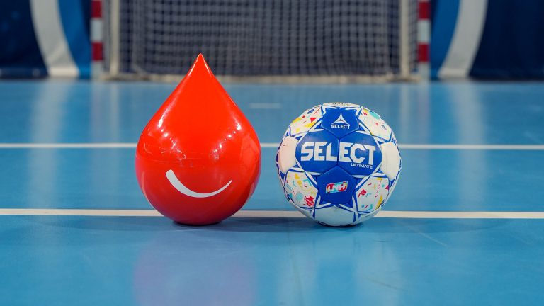 Ballon de handball et mascotte rouge sur le terrain.