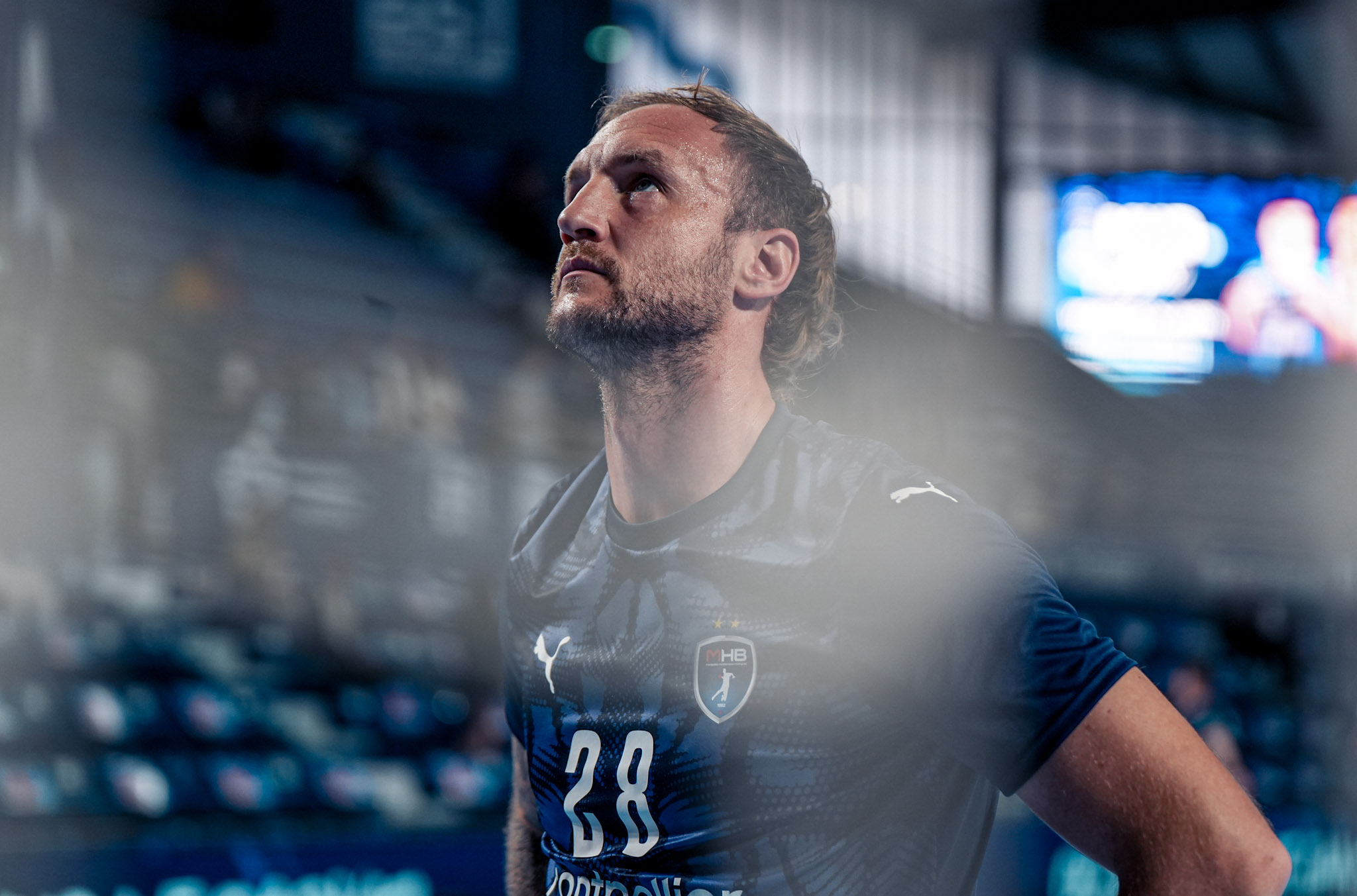 Joueur de handball en maillot bleu regardant en haut.