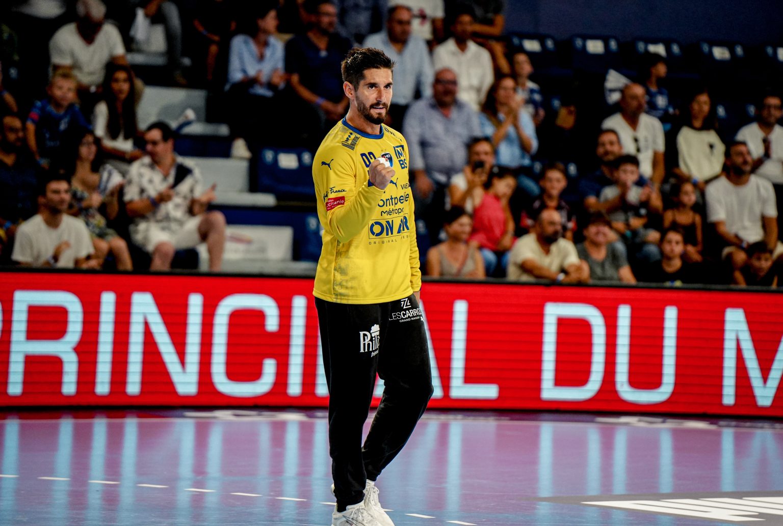 Joueur de handball sur le terrain devant spectateurs.
